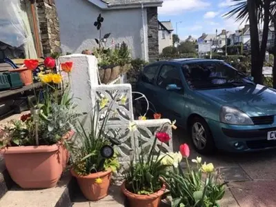 a blue car parked in front of a house with flowers at Aquarius B&B in Newquay