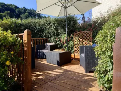 a patio with an umbrella and chairs on a deck at dog friendly nancecliff cottages in Looe