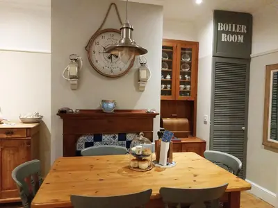 a dining room with a table and a clock on the wall at dog friendly nancecliff cottages in Looe