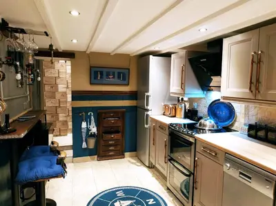 a kitchen with white cabinets and blue accents at dog friendly nancecliff cottages in Looe