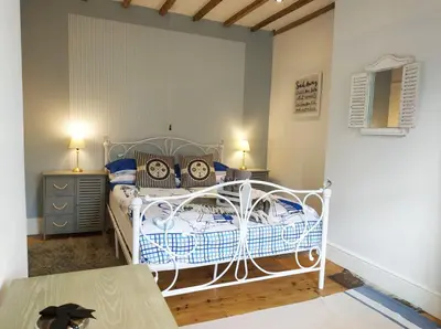 a bedroom with a white bed and a table at dog friendly nancecliff cottages in Looe