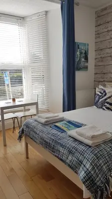 a bedroom with a bed and a table and a window at Saltwater in St Ives