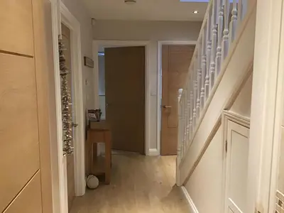 a hallway with stairs leading to a room with a door at Sunnyside Cottage in Crantock