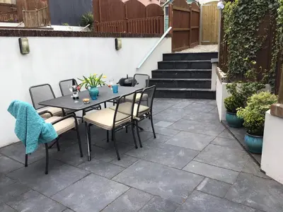a patio with a table and chairs and stairs at Sunnyside Cottage in Crantock