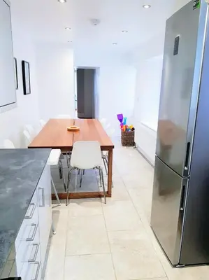 a kitchen with a wooden table and a refrigerator at Big, Beautiful, Cosy Falmouth House in Falmouth