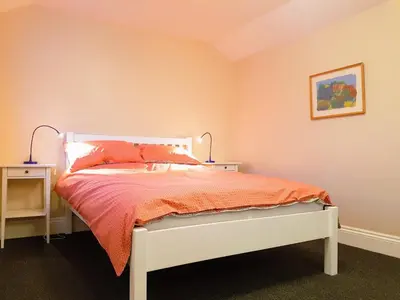 a bedroom with a white bed with an orange comforter at Big, Beautiful, Cosy Falmouth House in Falmouth