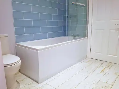 a bathroom with a tub and a toilet and blue tiles at Big, Beautiful, Cosy Falmouth House in Falmouth