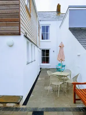 a patio with a table and chairs next to a building at Big, Beautiful, Cosy Falmouth House in Falmouth