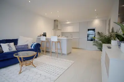 a living room with a blue couch and a kitchen at Saltwater Newquay in Newquay