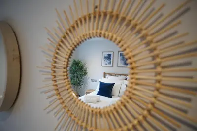 a mirror reflecting a bedroom with a bed and a couch at Saltwater Newquay in Newquay