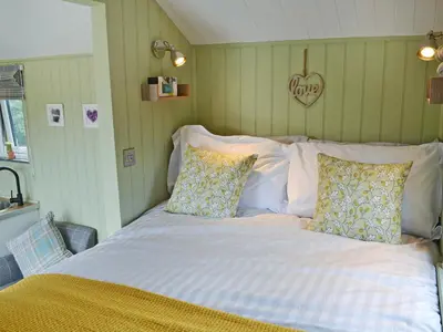 a bedroom with a large bed with white sheets and pillows at The Wool Shed in Saint Ewe