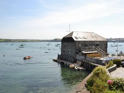 a building on a body of water with boats in it at Trelawny Court in Saint Minver