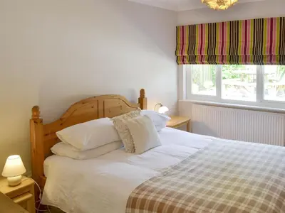 a bedroom with a bed with white sheets and a window at Trelawny Court in Saint Minver