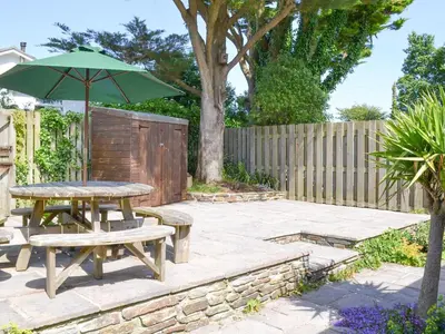 a patio with a picnic table and an umbrella at Trelawny Court in Saint Minver