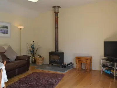 a living room with a wood stove in the corner at Welly's Wallow in Saint Kew