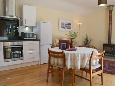 a kitchen with a table and chairs and a kitchen with white appliances at Welly's Wallow in Saint Kew