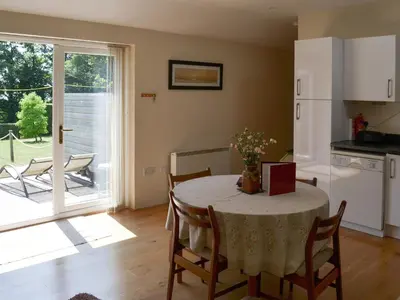 a kitchen and dining room with a table and a kitchen with a patio at Welly's Wallow in Saint Kew