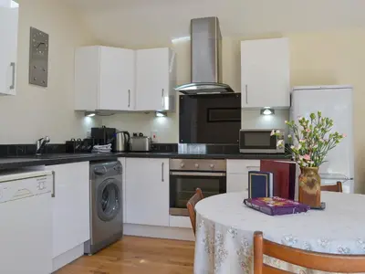 a kitchen with a table with a vase of flowers at Welly's Wallow in Saint Kew