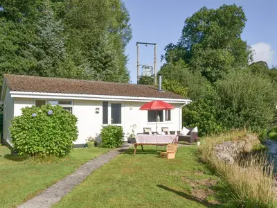 a white house with a picnic table in the yard at Westville By The Stream in Saint Cleer