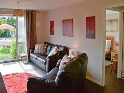 a living room with a leather couch and a table at Westville By The Stream in Saint Cleer