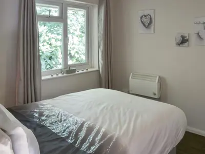a white bedroom with a bed and a window at Westville By The Stream in Saint Cleer