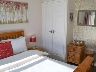 a bedroom with a bed with a red pillow and a door at Westville By The Stream in Saint Cleer