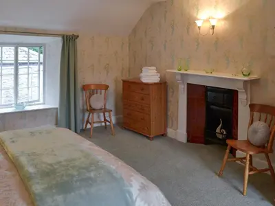 a bedroom with a bed and chairs and a fireplace at The Farmhouse in Lostwithiel