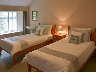 a bedroom with two beds and a sink in it at The Farmhouse in Lostwithiel