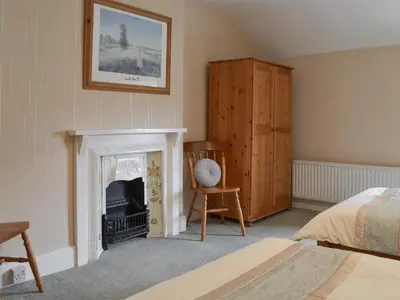 a bedroom with a fireplace and a bed and a chair at The Farmhouse in Lostwithiel