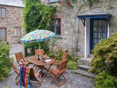a table and chairs with an umbrella in front of a building at The Farmhouse in Lostwithiel