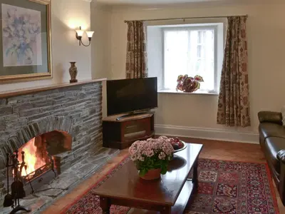 a living room with a fireplace and a television at The Farmhouse in Lostwithiel