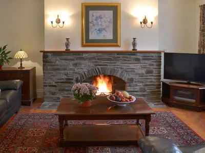 a living room with a fireplace with a bowl of fruit at The Farmhouse in Lostwithiel