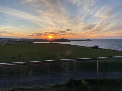a sunset over a field with the ocean in the background at Ocean View Beach Rd in Newquay