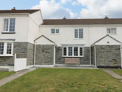 a white house with a bench in the front yard at Bayview in Newquay