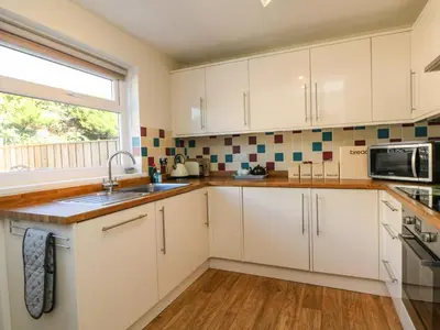 a kitchen with white cabinets and a window at Bayview in Newquay