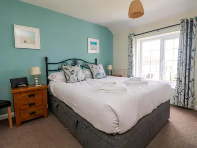 a bedroom with a large bed with blue walls and a window at Bayview in Newquay
