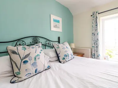 a bedroom with a white bed with blue walls at Bayview in Newquay