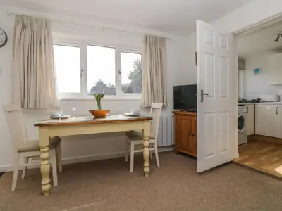a room with a table with chairs and a kitchen at Cockle Island Cottage in Porthallow