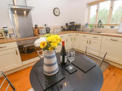 a kitchen with a table with a bottle of wine and flowers at Godrevy Barn in Hayle