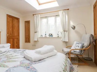 a bedroom with a bed and a chair and a window at Godrevy Barn in Hayle