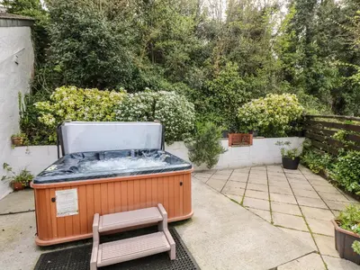 a hot tub sitting on a patio with a bench at Godrevy Barn in Hayle