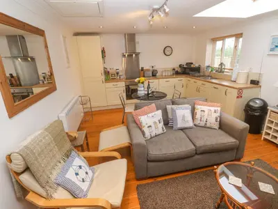 a living room with two couches and a kitchen at Godrevy Barn in Hayle