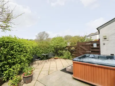 a hot tub on a patio with a garden at Godrevy Barn in Hayle