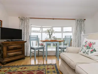 a living room with a couch and a table with chairs at Rosa Cottage in Porthleven