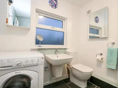 a bathroom with a washing machine and a sink at Rosa Cottage in Porthleven