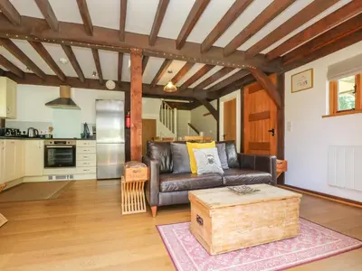 a living room with a leather couch and a kitchen at Oaklands in Camelford