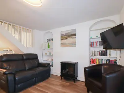 a living room with a leather couch and a fireplace at Alma House 2 in Perranporth