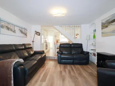 a living room with a leather couch and two chairs at Alma House 2 in Perranporth