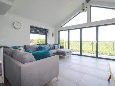 a living room with a couch and some windows at Trenant View in Wadebridge