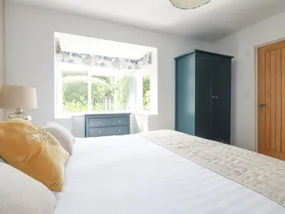 a bedroom with a white bed and a window at Trenant View in Wadebridge